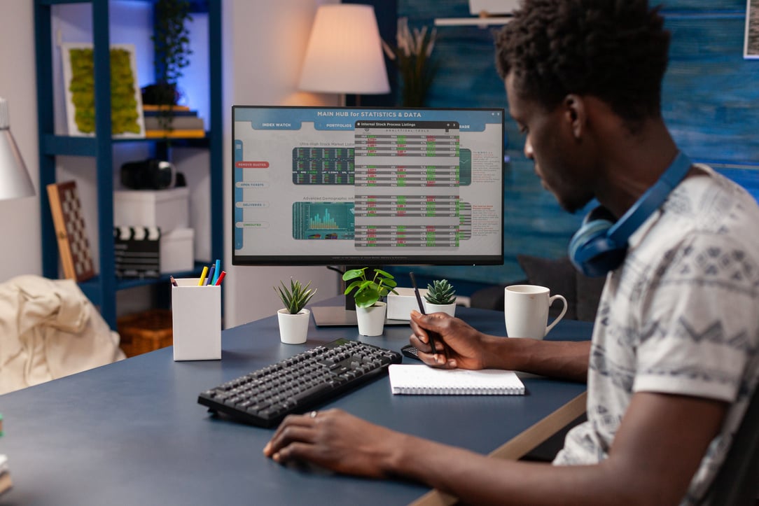 African american trader writing crypto currency data on notebook